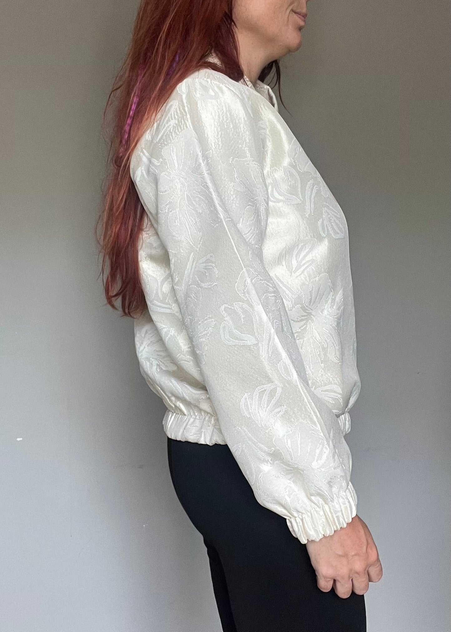 Champagnekleurig semi bomberjasje van glanzende stof met bloemenprint, rits en steekzakken. Vrouwelijk, trendy en one size.