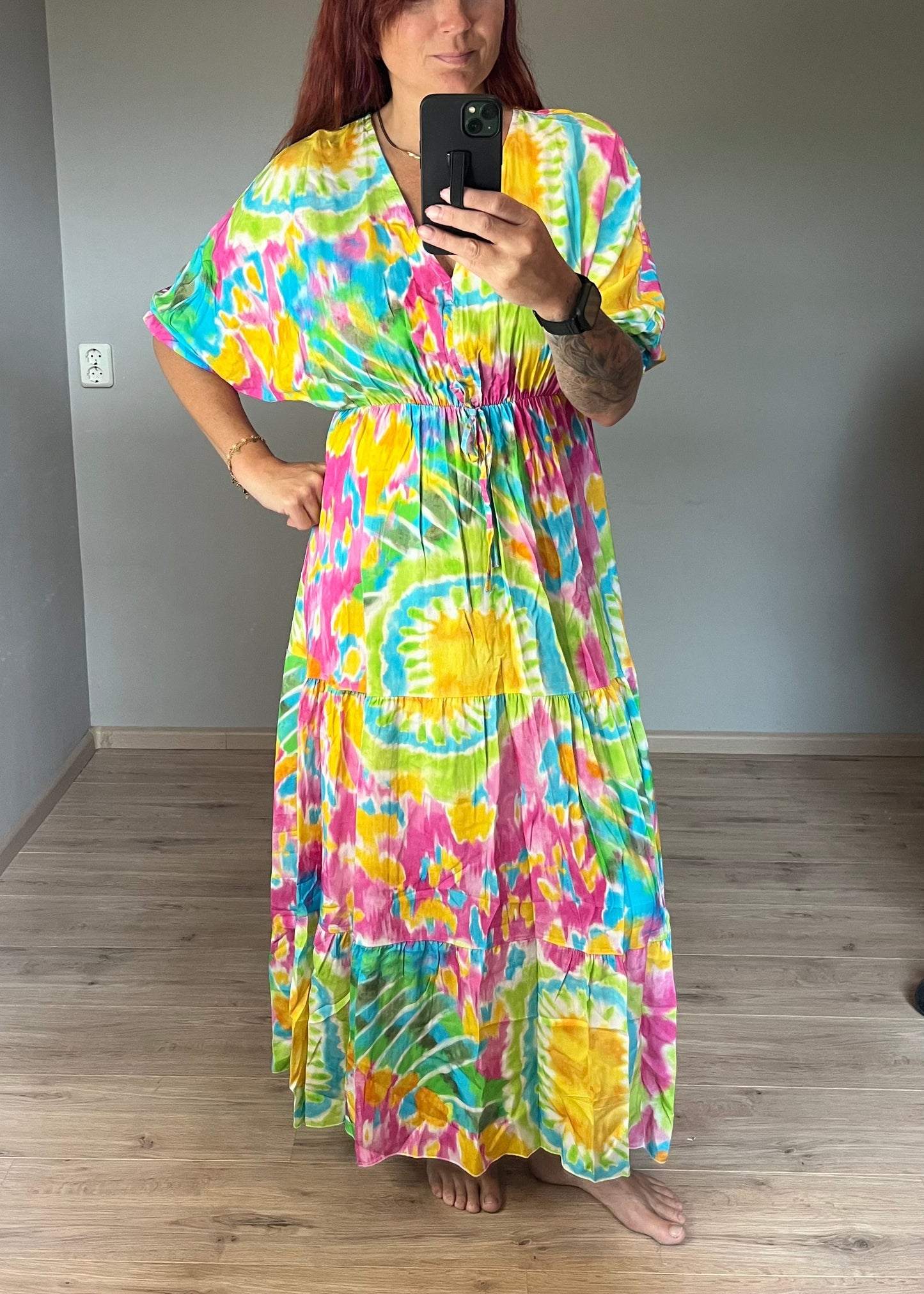Vrouwelijke zomerjurk van viscose met knalkleuren print, elastiek onder de borst en wijde mouwen. Luchtig model, knoopsluiting op de rug.