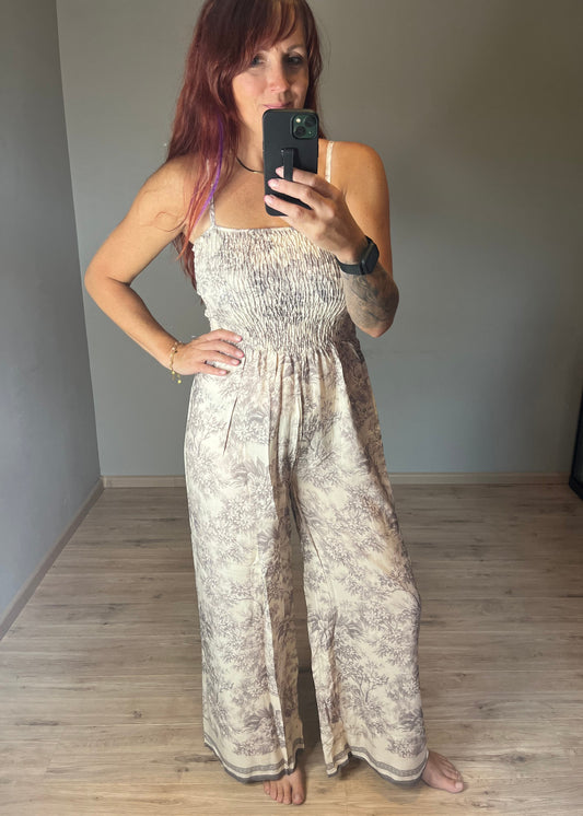 Dames jumpsuit van viscose in beige-grijze Soft Taupe Print met spaghetti bandjes en gesmokt lijfje. Verkrijgbaar in maat S, M en L.