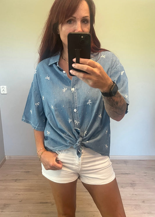 Oversized damesblouse van denim met strikjes en glitters, gemaakt van katoen. One size, passend tot maat 46.