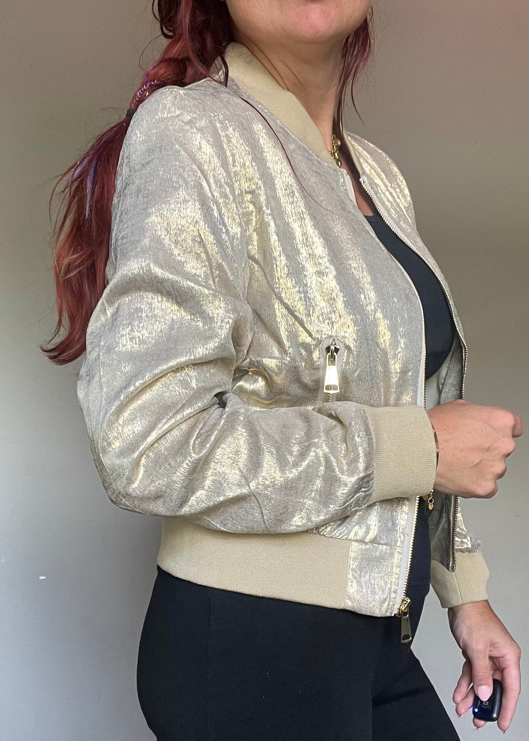 Metallic bomberjasje in goud of zilver met rits en steekzakken. Trendy, vrouwelijk model voor zomer en najaar.