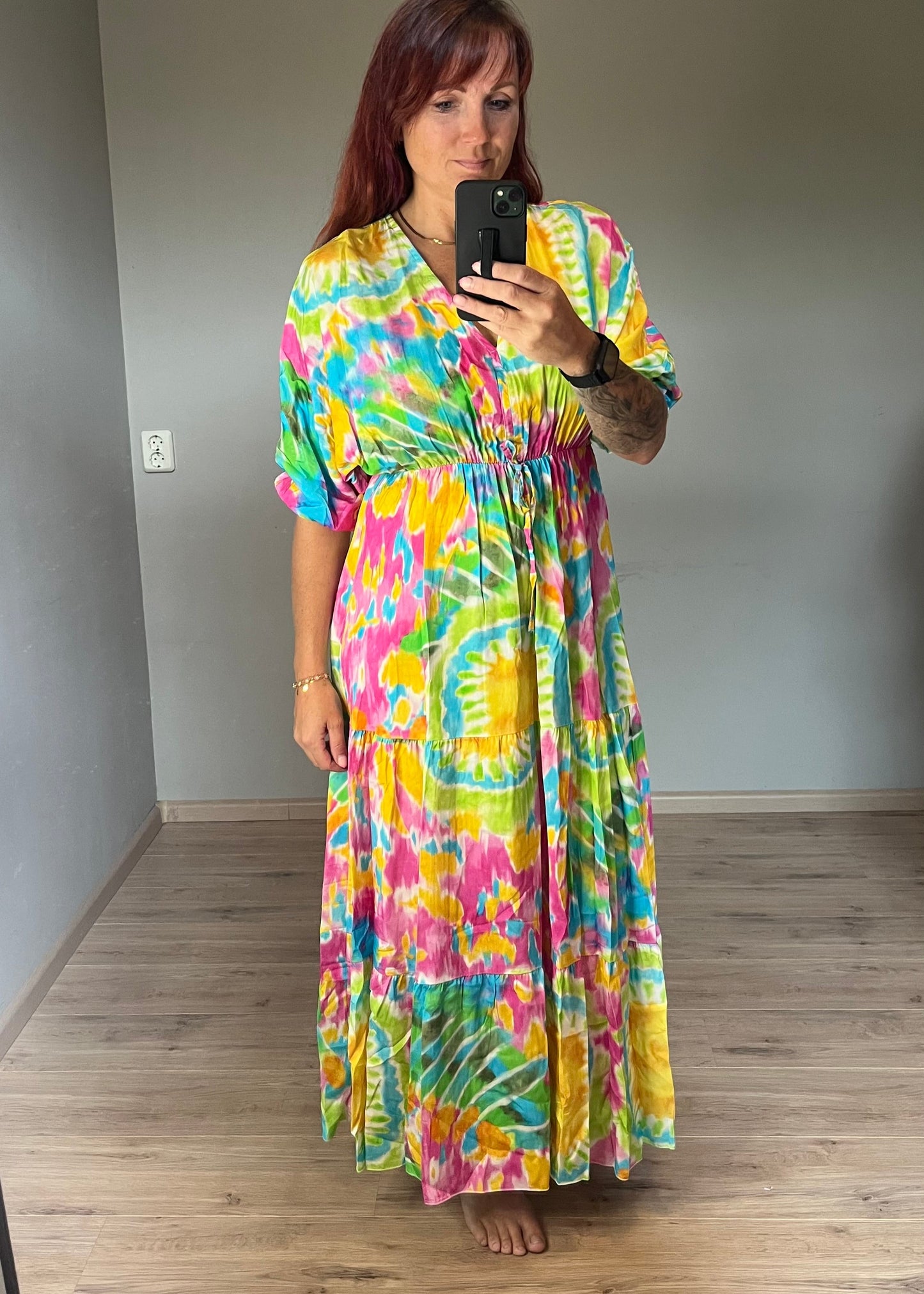 Vrouwelijke zomerjurk van viscose met knalkleuren print, elastiek onder de borst en wijde mouwen. Luchtig model, knoopsluiting op de rug.