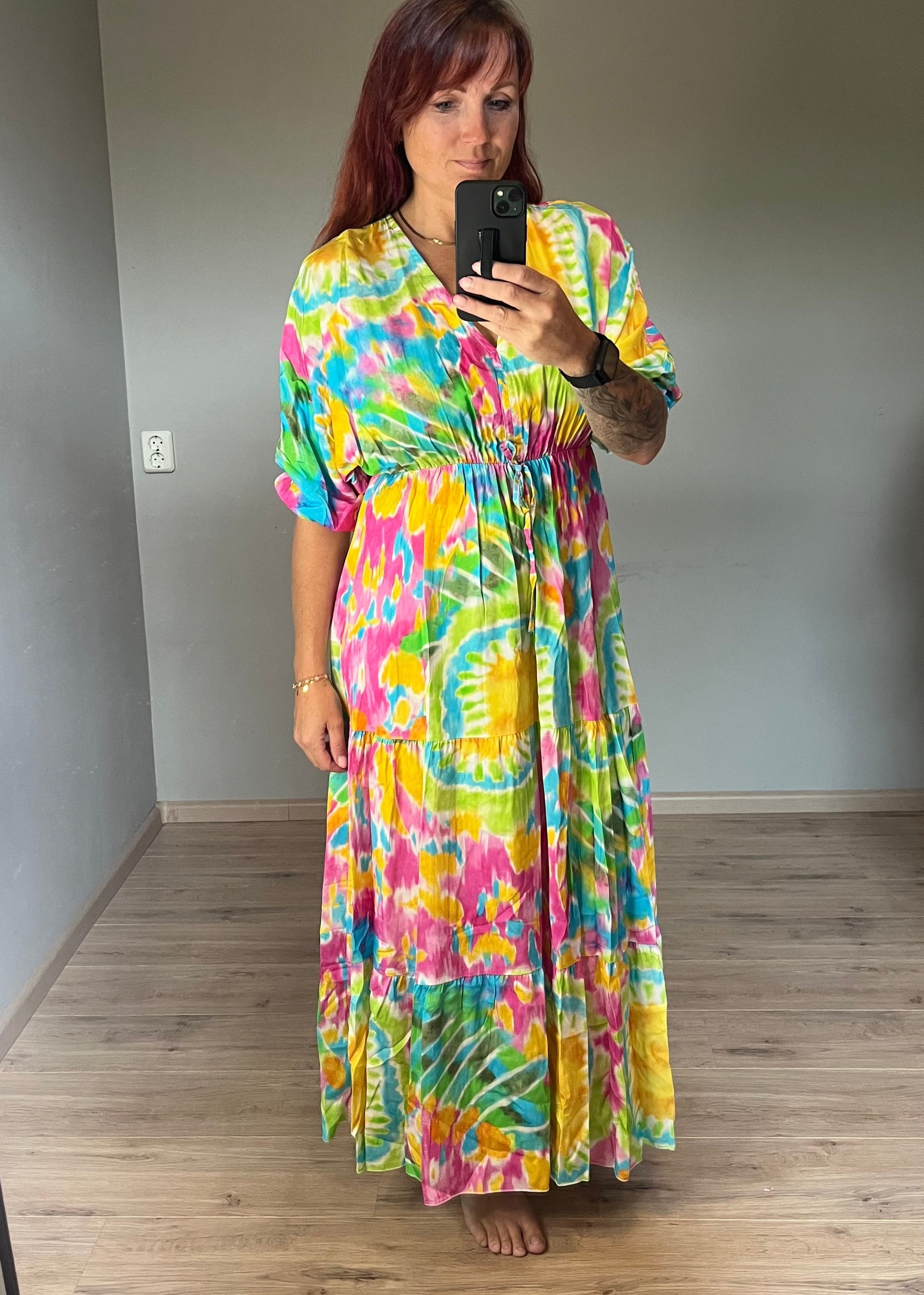 Vrouwelijke zomerjurk van viscose met knalkleuren print, elastiek onder de borst en wijde mouwen. Luchtig model, knoopsluiting op de rug.