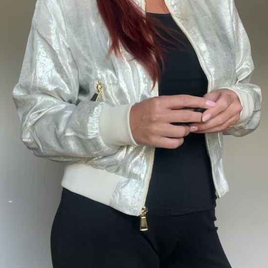 Metallic bomberjasje in goud of zilver met rits en steekzakken. Trendy, vrouwelijk model voor zomer en najaar.